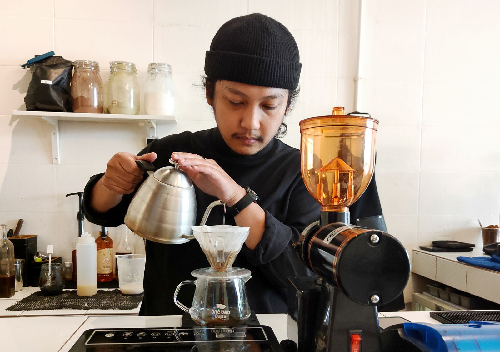 Barista carefully brewing pour-over coffee in a cafe